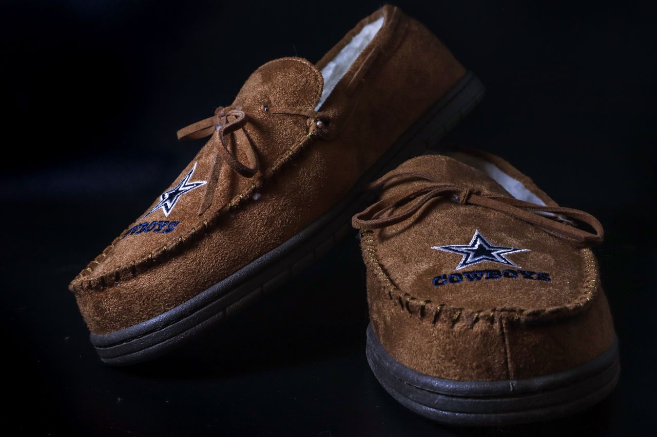 Brown suede loafers with star embroidery, close-up shot with elegant black background.