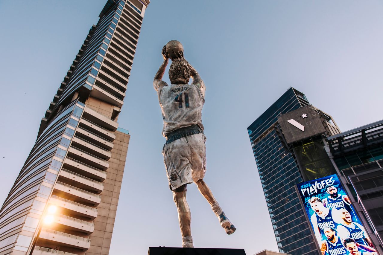 Dynamic statue with basketball skyscraper backdrop showcasing urban architecture.