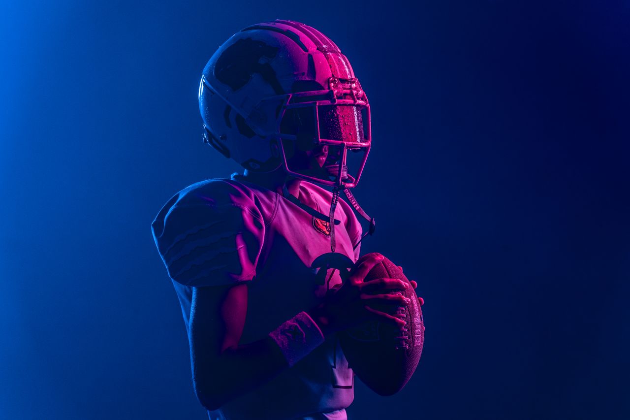 Young athlete in football gear with bold lighting for a dramatic effect.