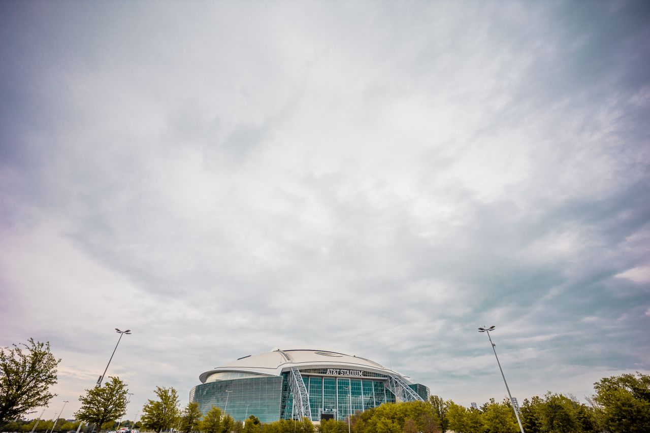 services-02 Wide-angle view of AT&T Stadium under dramatic clouds highlighting modern architectural design.